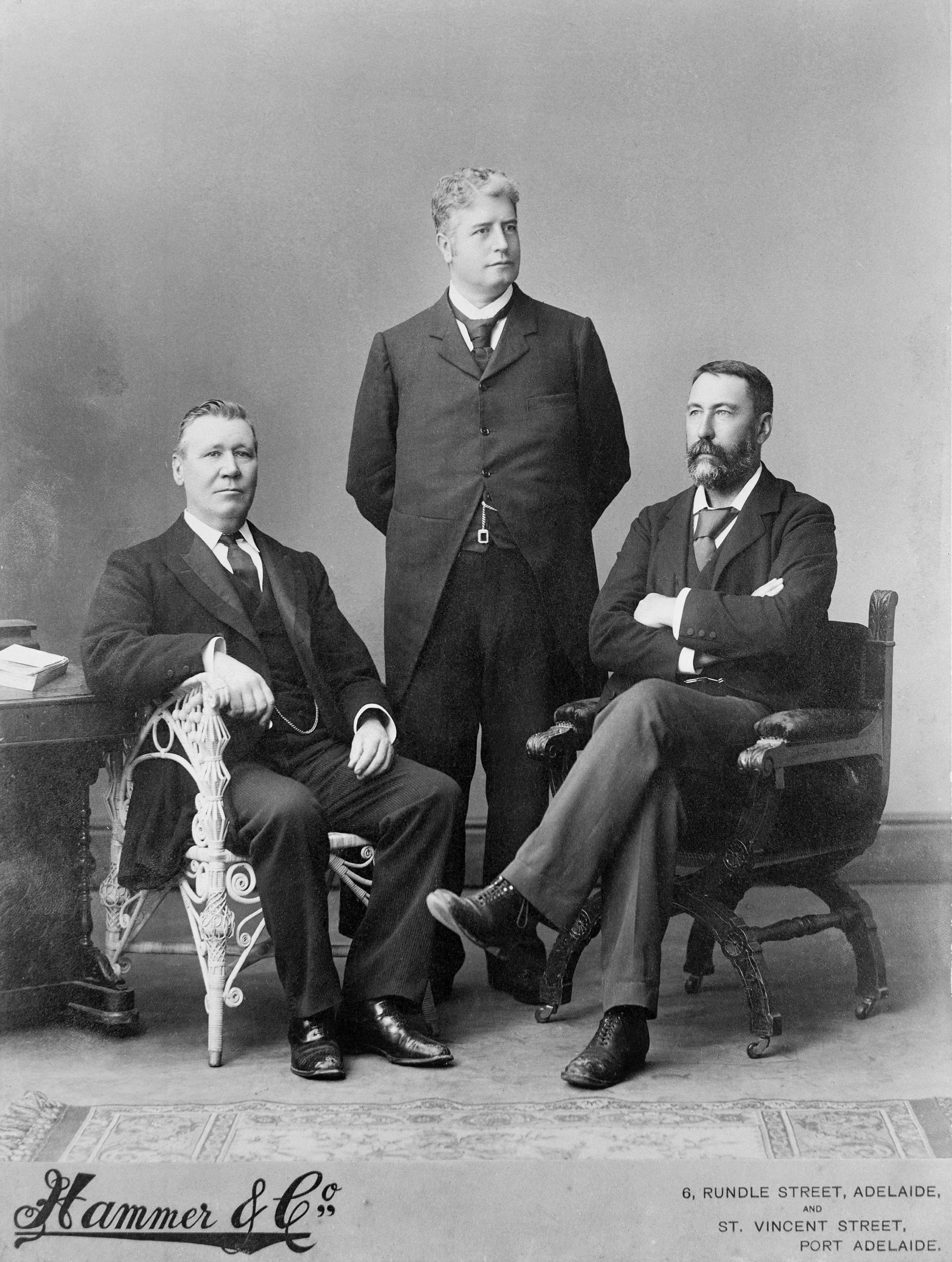 Black and white portrait of three well dressed men posing for a portrait.  