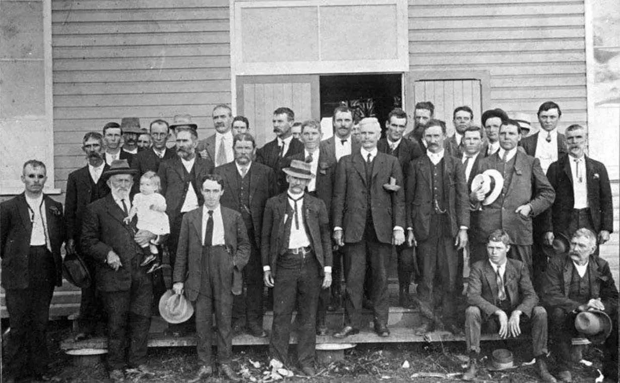 Andrew Fisher and a group of farmers pose in front of a building. 