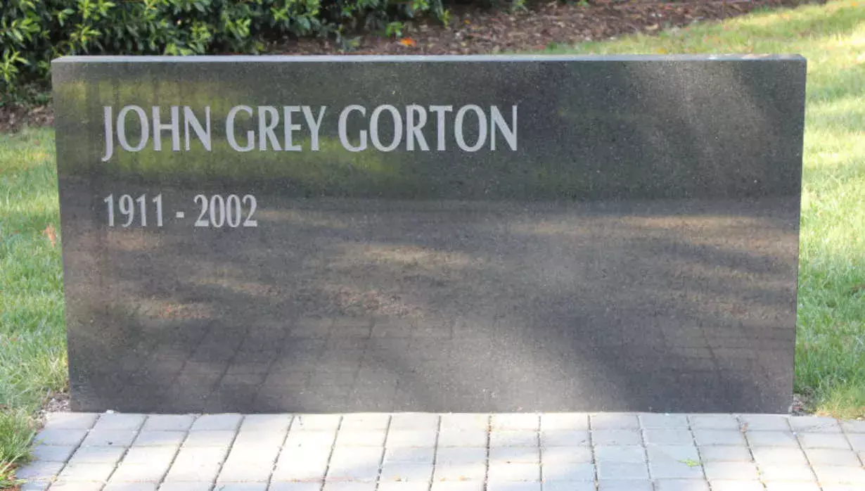 A dark grey rectangular stone memorial that rises from the ground is inscribed with the words 'John Grey Gorton, 1911-2002; 