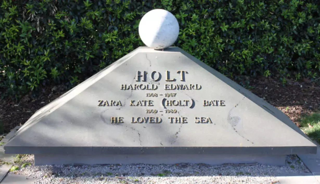 A pyramid-shaped small stone memorial with a sphere balanced on top. The inscription reads 'Harold Edward Holt, Zara Kate Holt, he loved the sea'. 