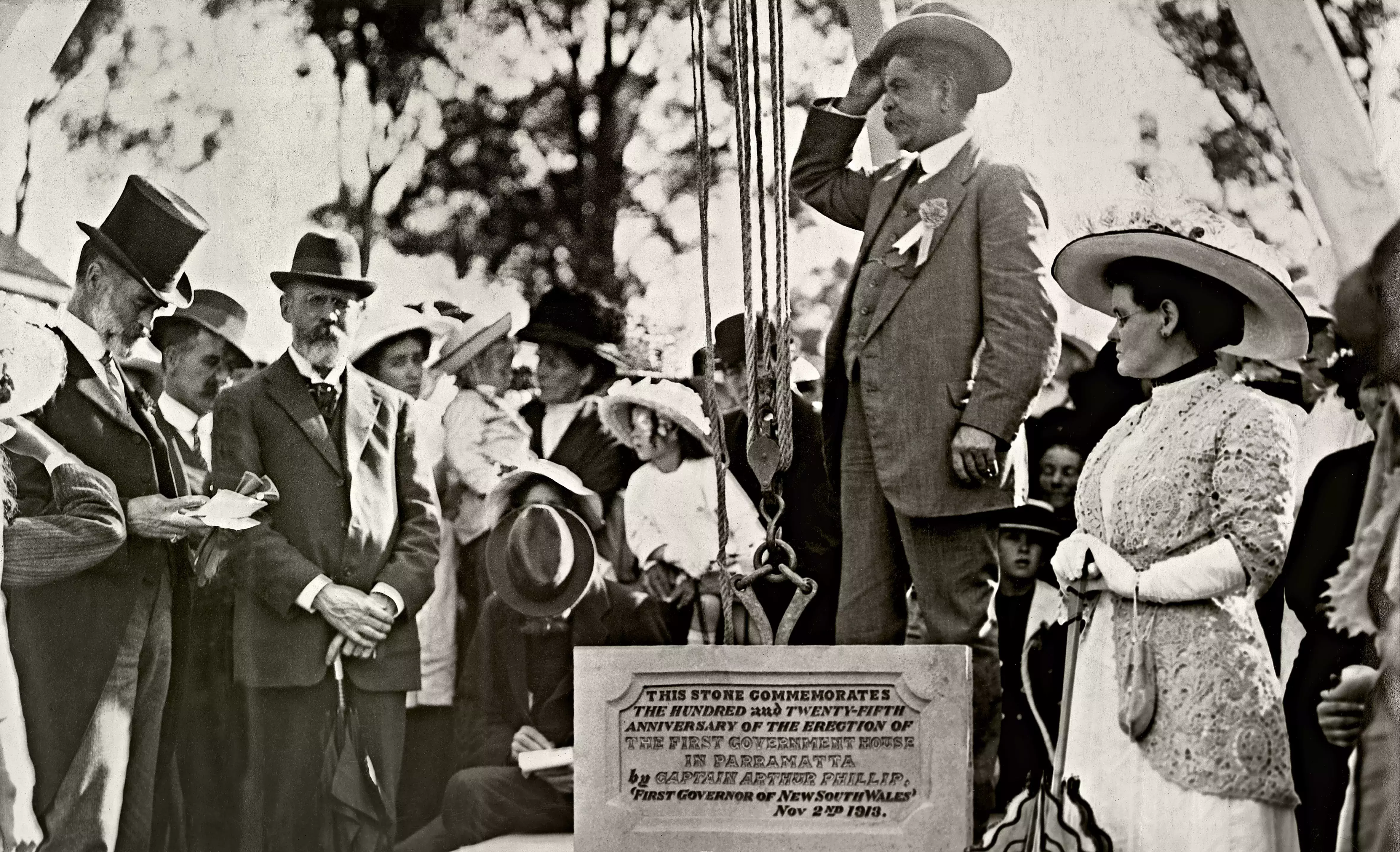 A man stands on a soap box surrounded by people. Joseph Cook looks at him from the crowd. 