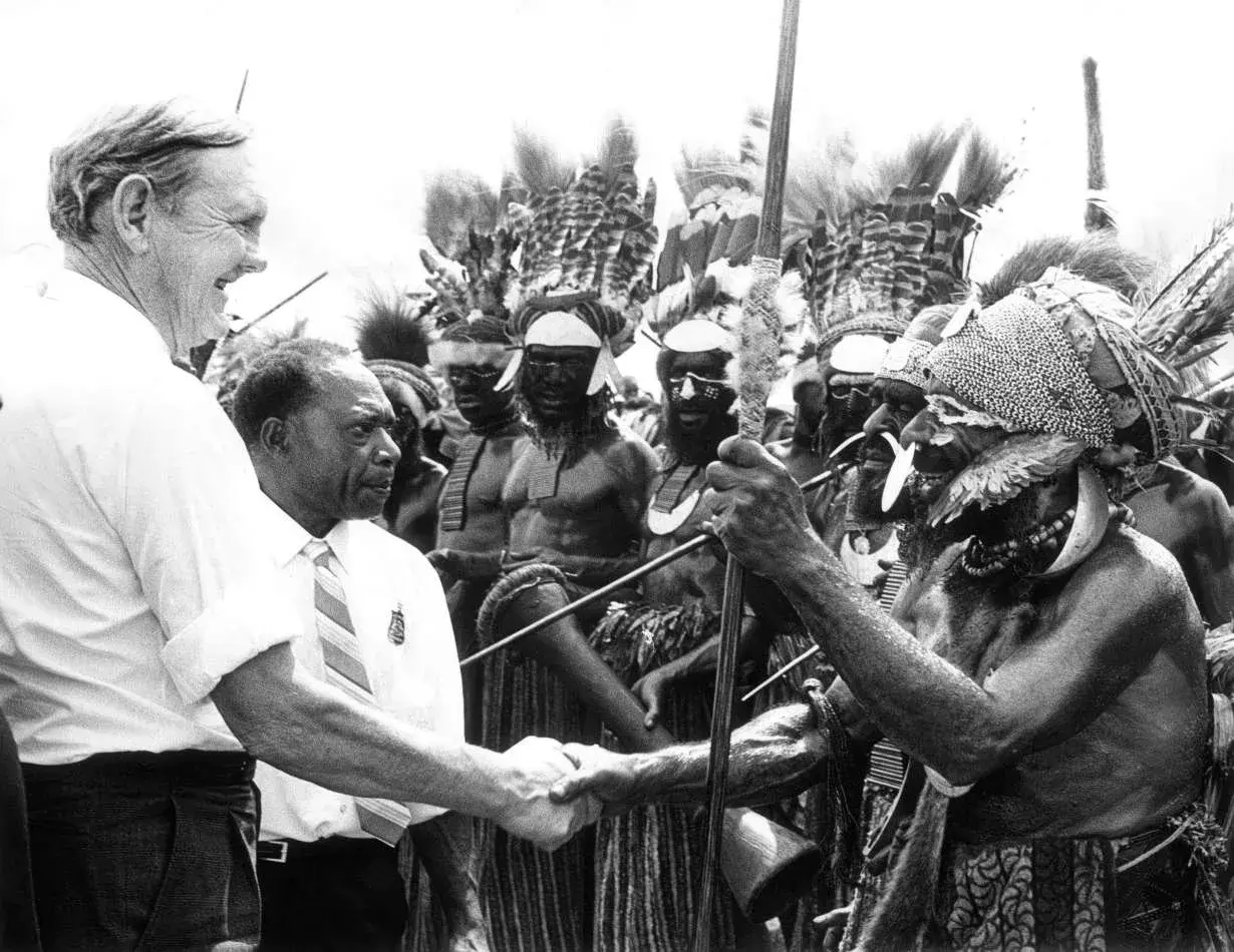 John Gorton shakes hands with a man in Papua New Guinea.