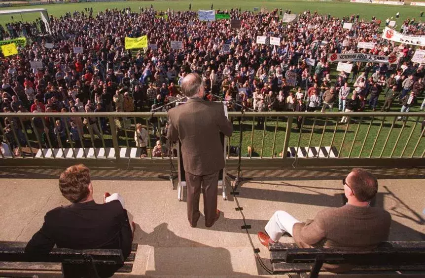 John Howard looks out at rally while he stands on an elevated platform to give a speech.  