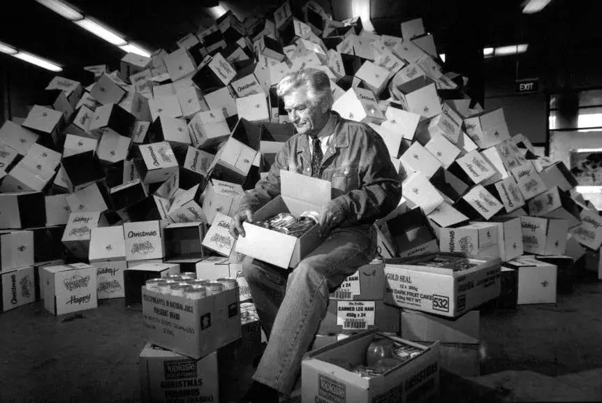 Bob Hawke sits on a carton surrounded by cartons. 