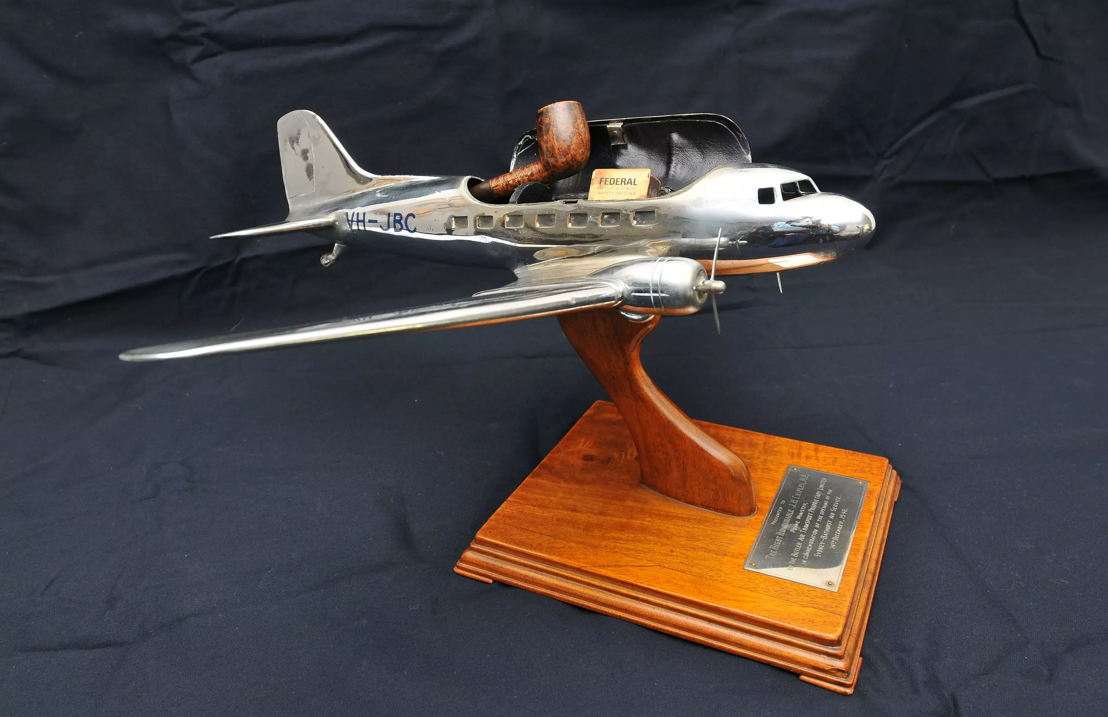 A silver model plane on a wooden base. 