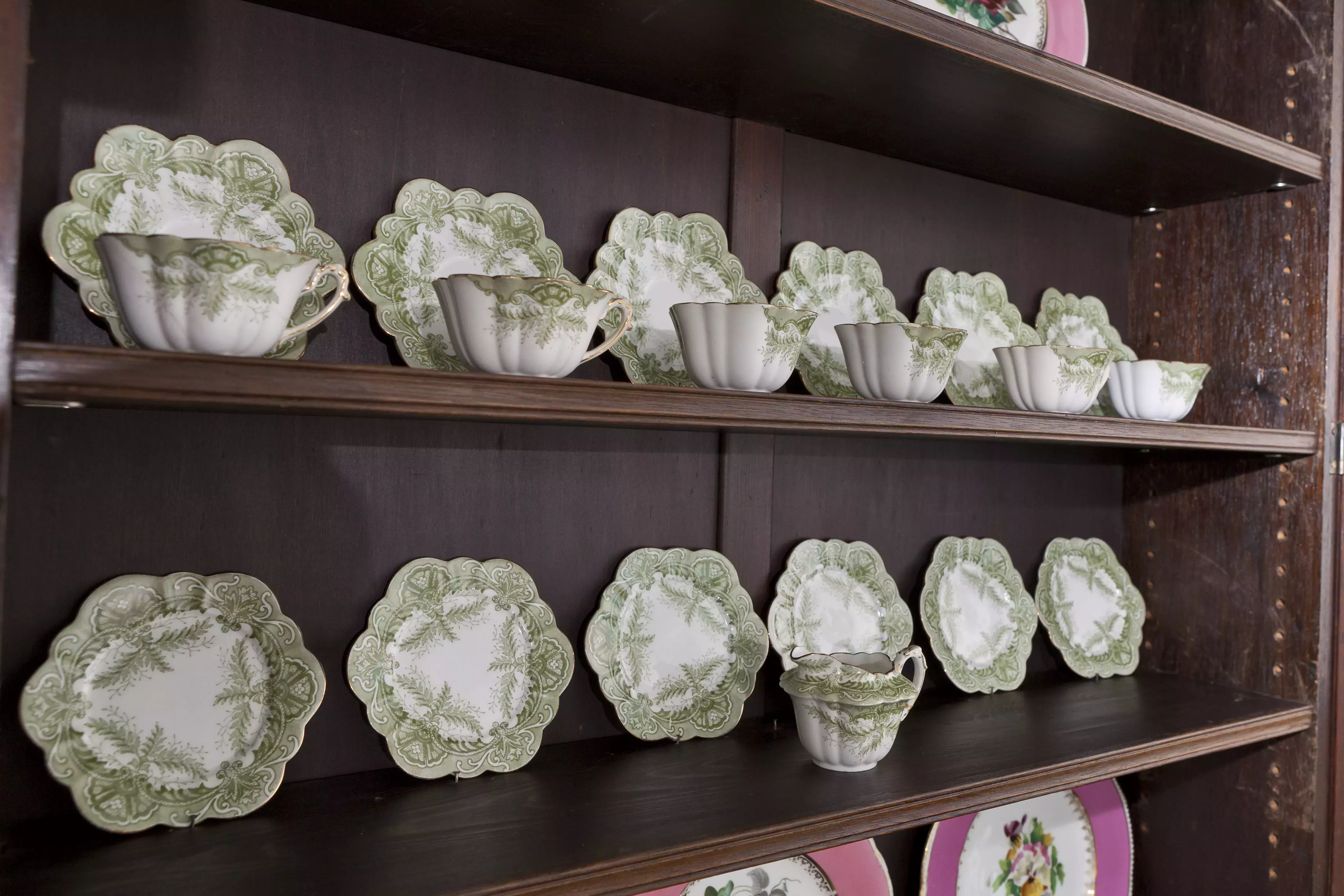 A green and white tea set on a shelf 