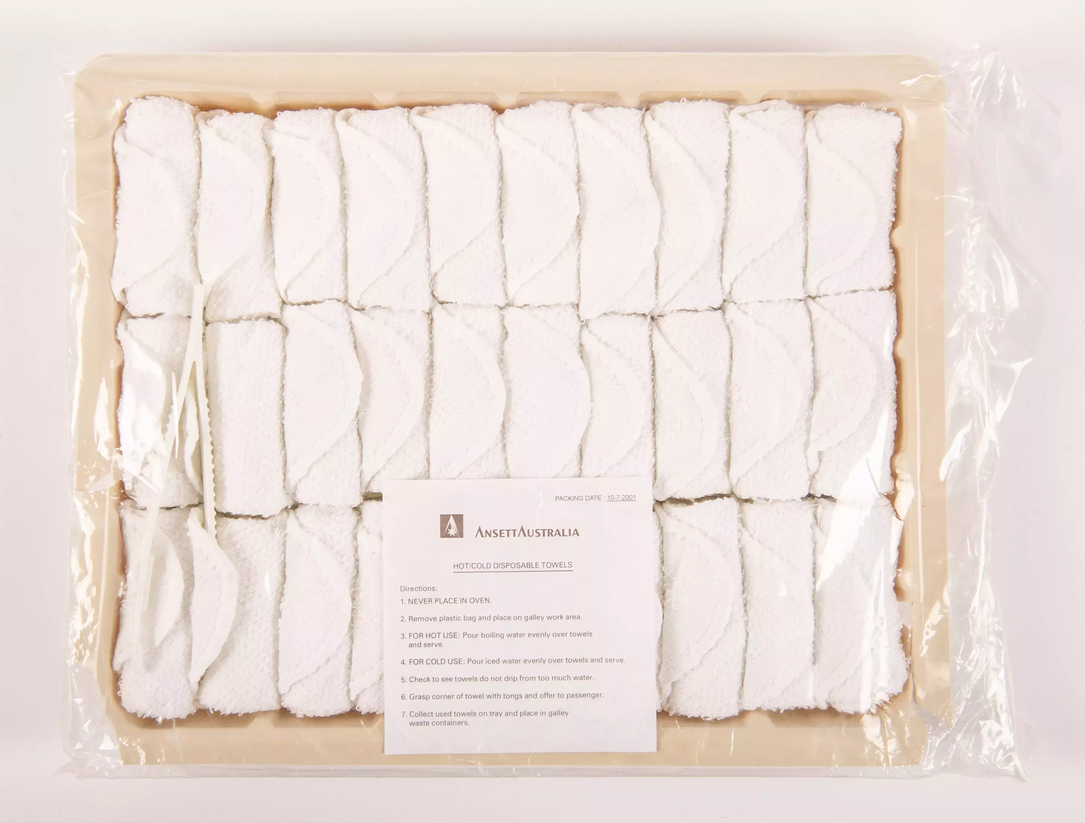A box of small white towels rolled up and placed next to each in 3 rows covered in plastic.
