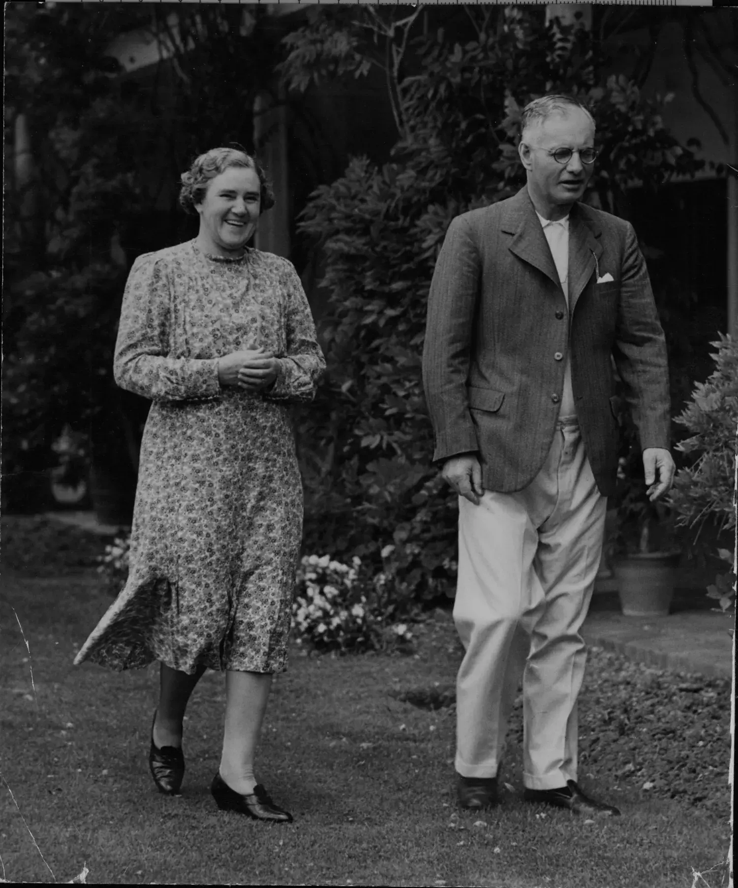 A black and white photo of John and Elsie Curtin walking in the backyard.  